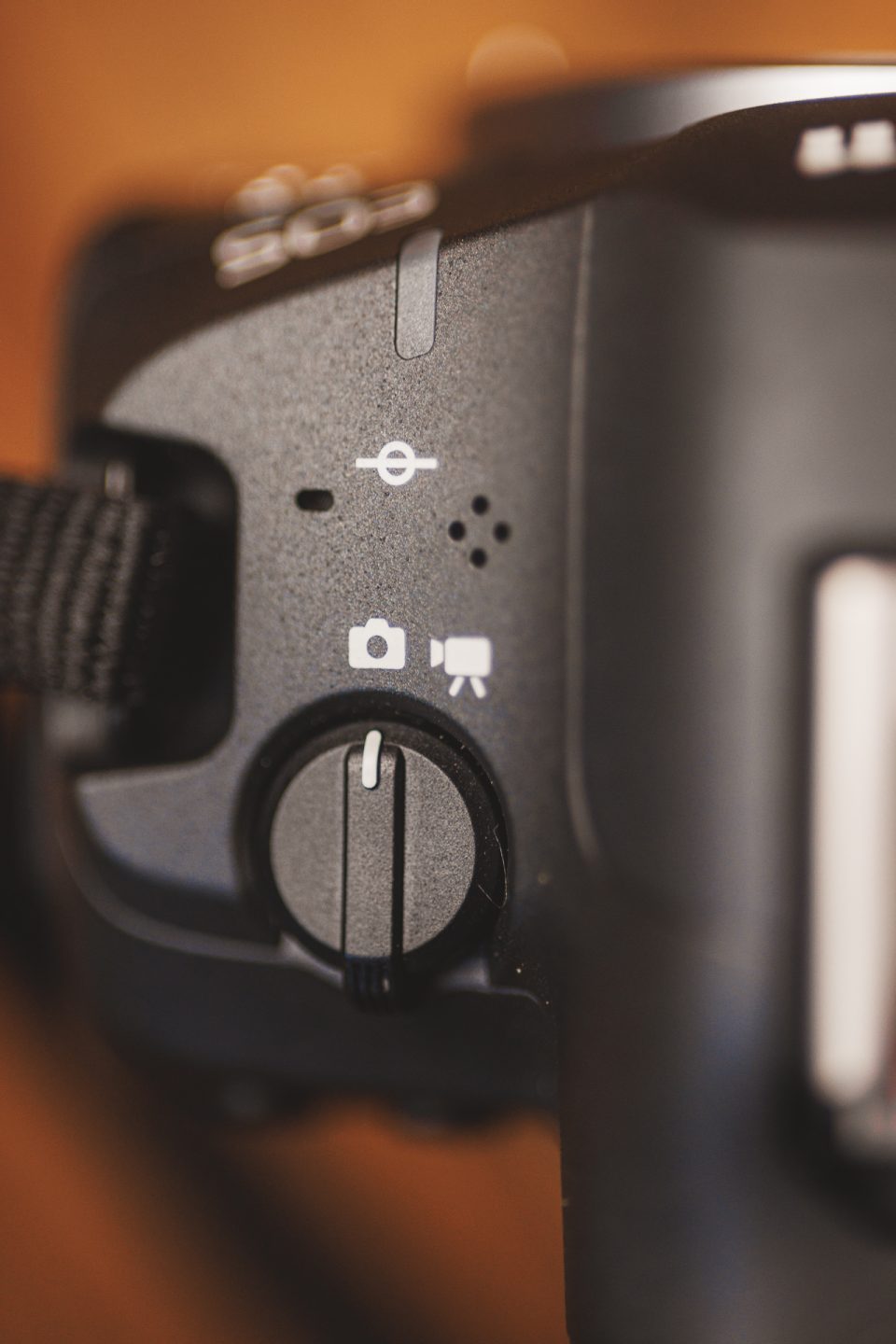 Close-up of a camera mode dial set to video recording, with icons for photo and video modes visible.